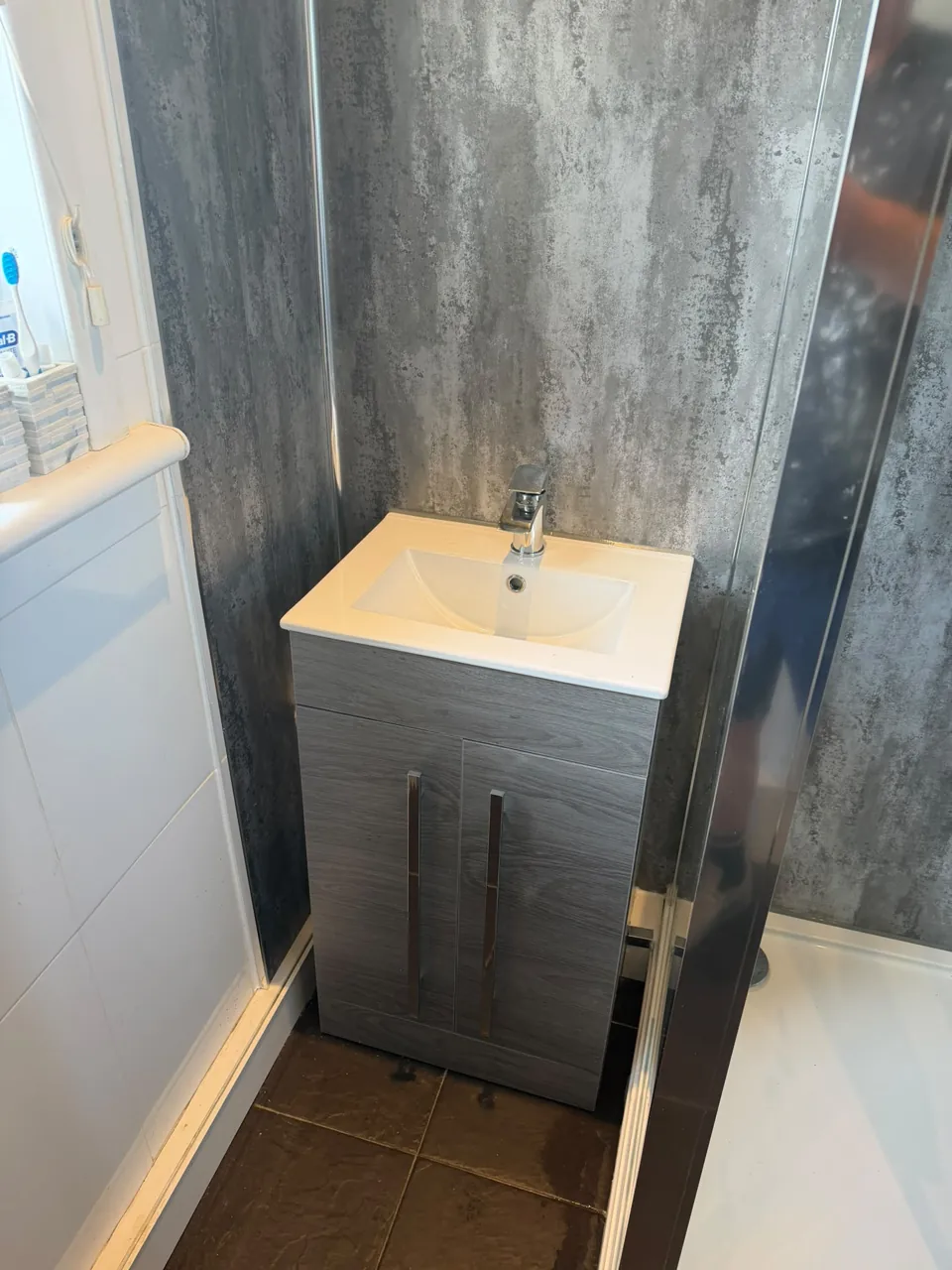 Grey vanity and basin beside the shower enclosure