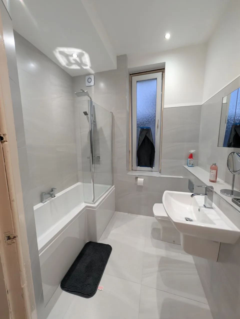 White fitted bath and shower screen with grey walls