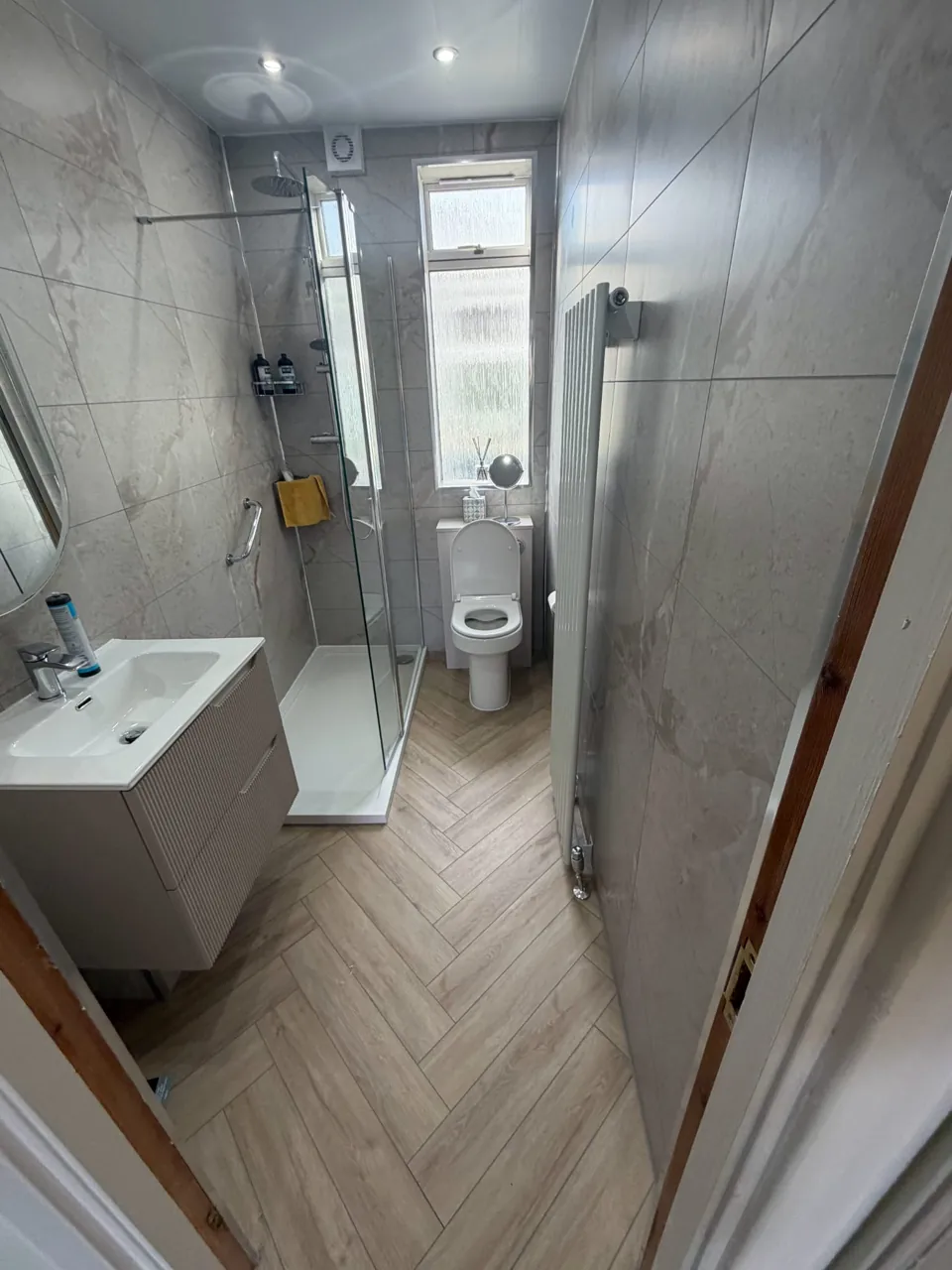 Narrow marble-effect shower room with white bathroom furniture